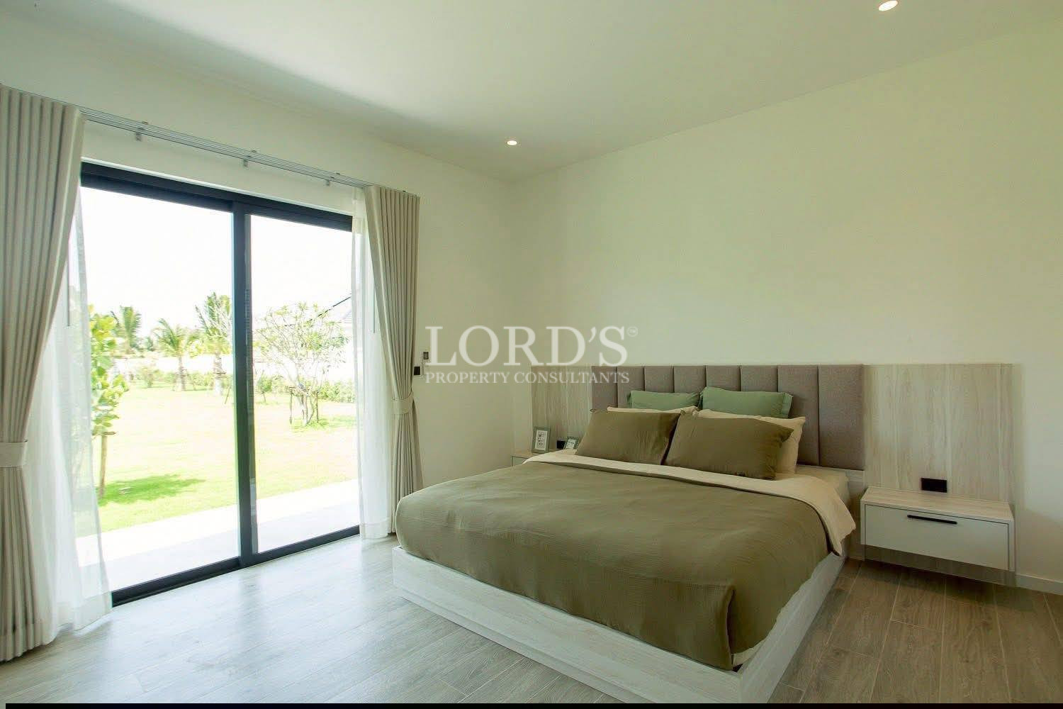 Modern bedroom with sliding glass doors, garden view, and neutral bedding.