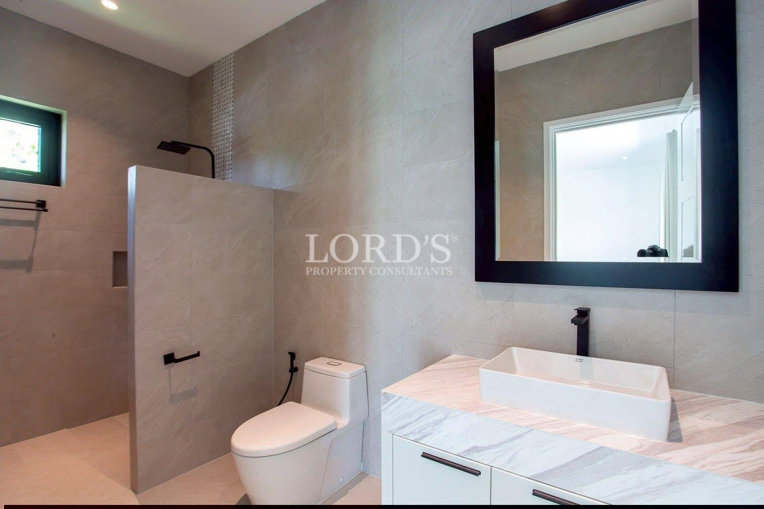 Modern bathroom with walk-in shower, wall-mounted vanity, vessel sink, and black-framed mirror.