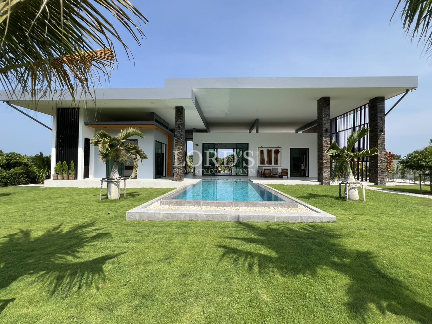Modern luxury villa with central swimming pool and landscaped lawn.