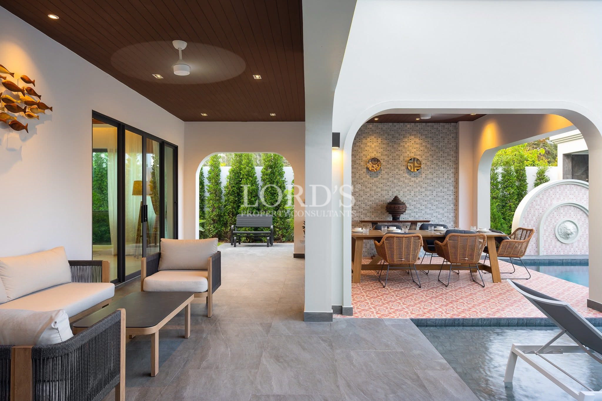 Covered outdoor patio with lounge seating, dining area, and poolside terrace.