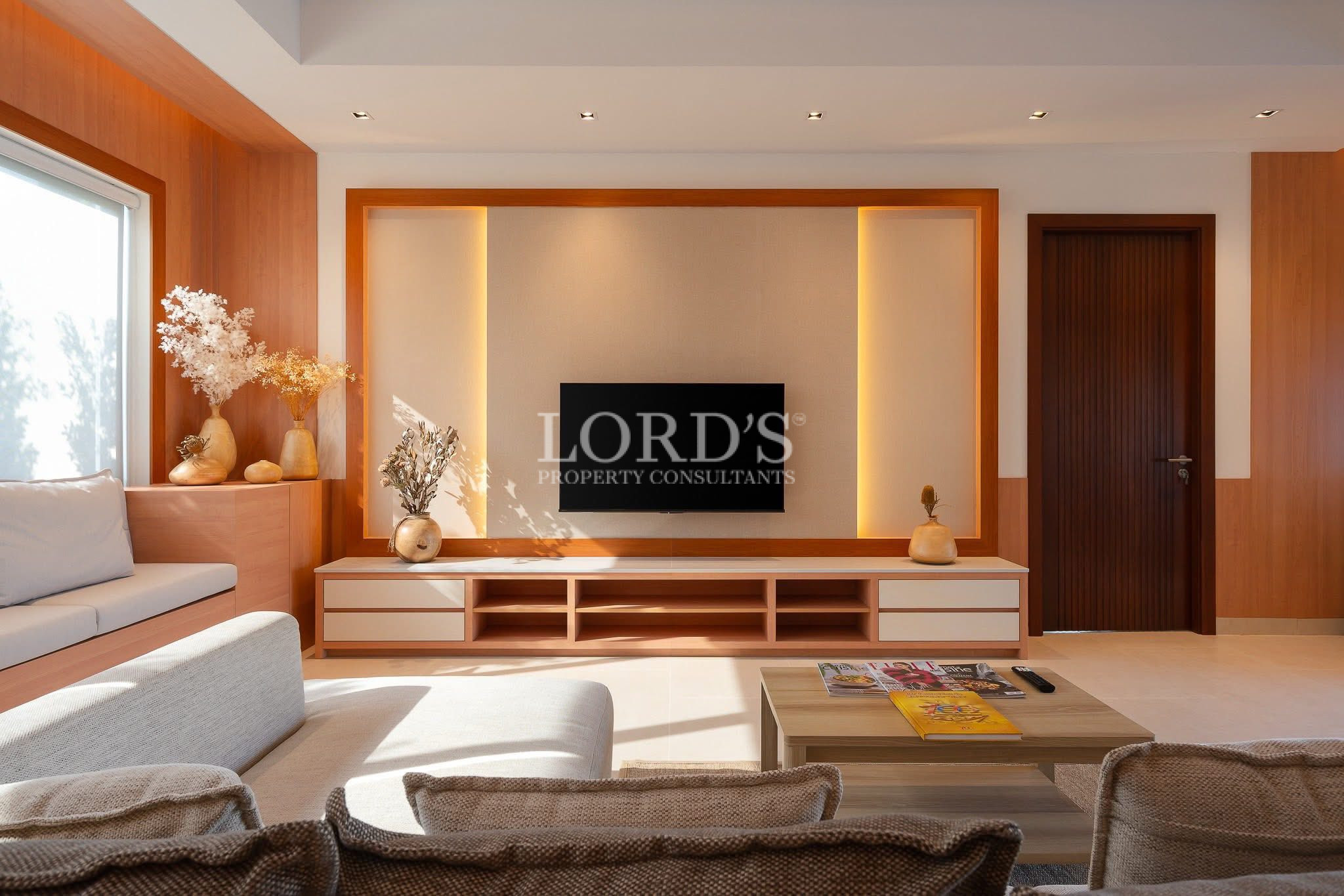 Modern living room with built-in TV wall, wooden accents, and minimalist seating area.