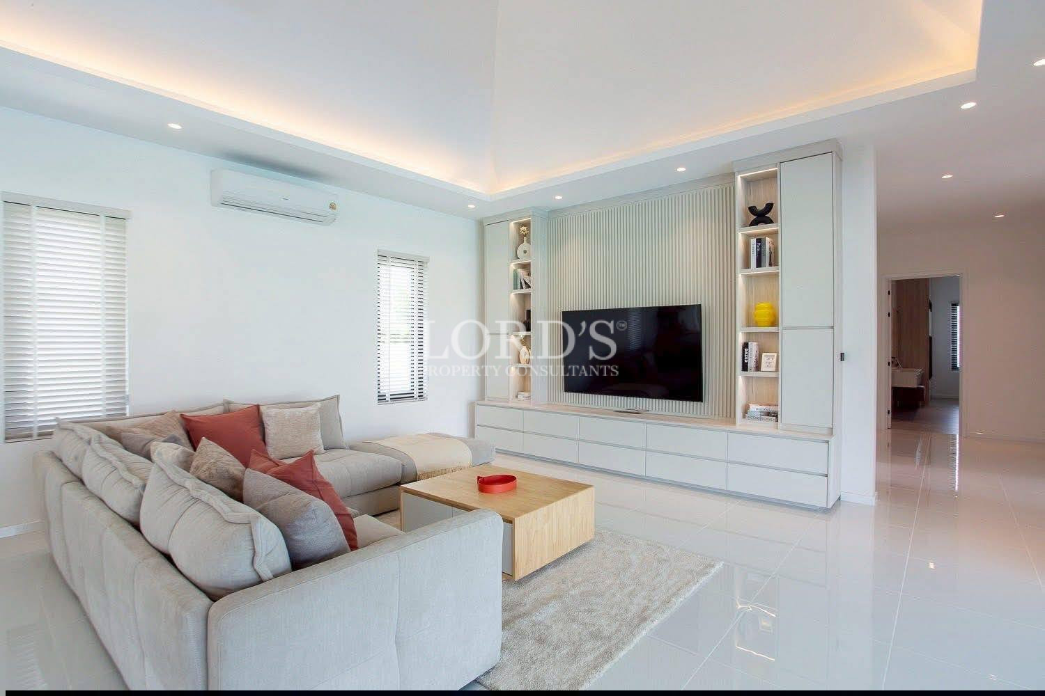 Modern living room with sectional sofa, built-in TV wall unit, and minimalist decor.