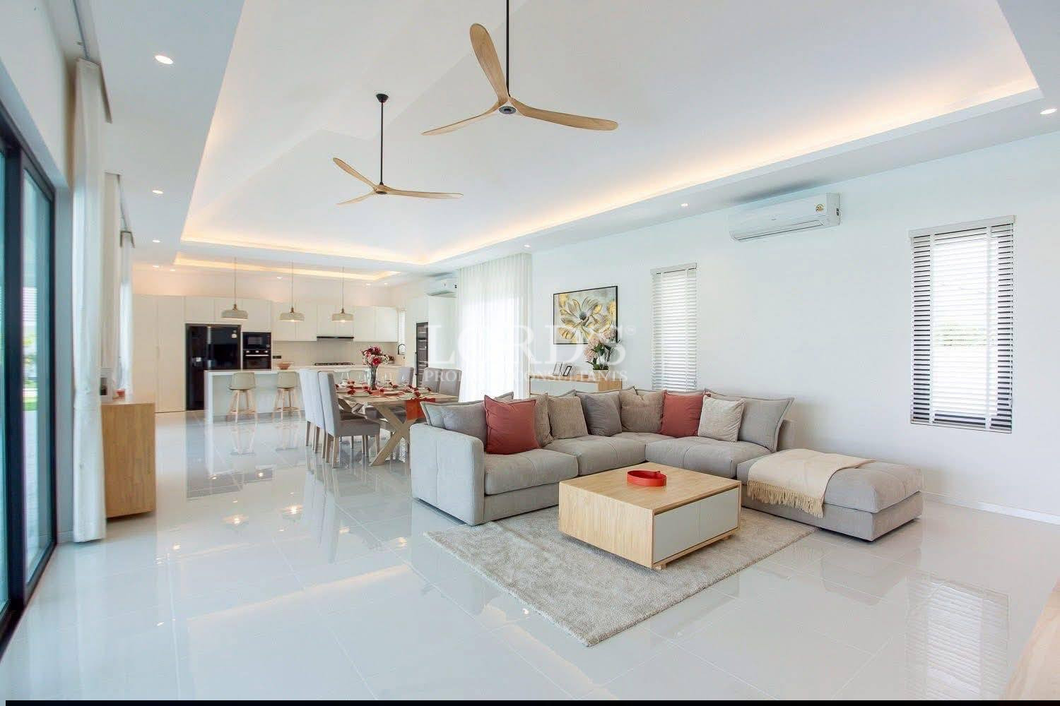 Modern open-plan living room with sectional sofa, dining area, and kitchen in bright contemporary home.