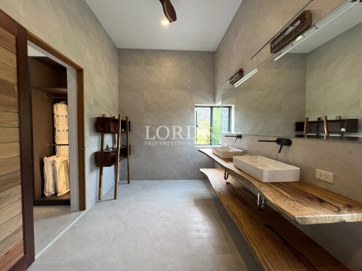 Modern bathroom with double vessel sinks, wooden vanity countertop, and large wall mirror.