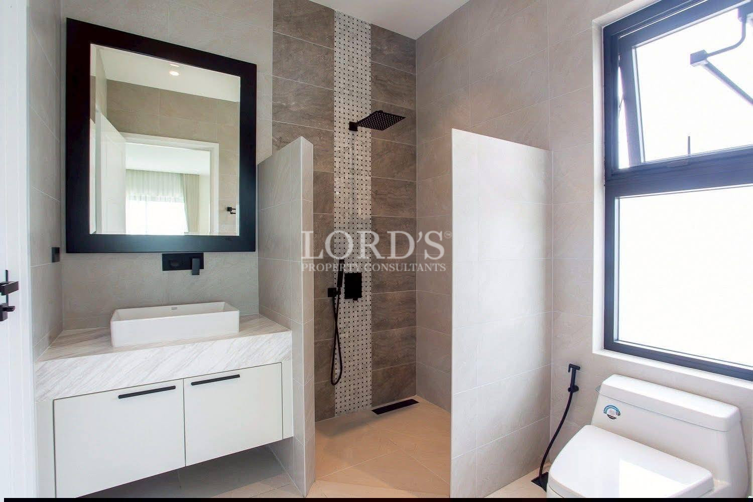 Modern bathroom with walk-in shower, black rain showerhead, vanity sink, and window.