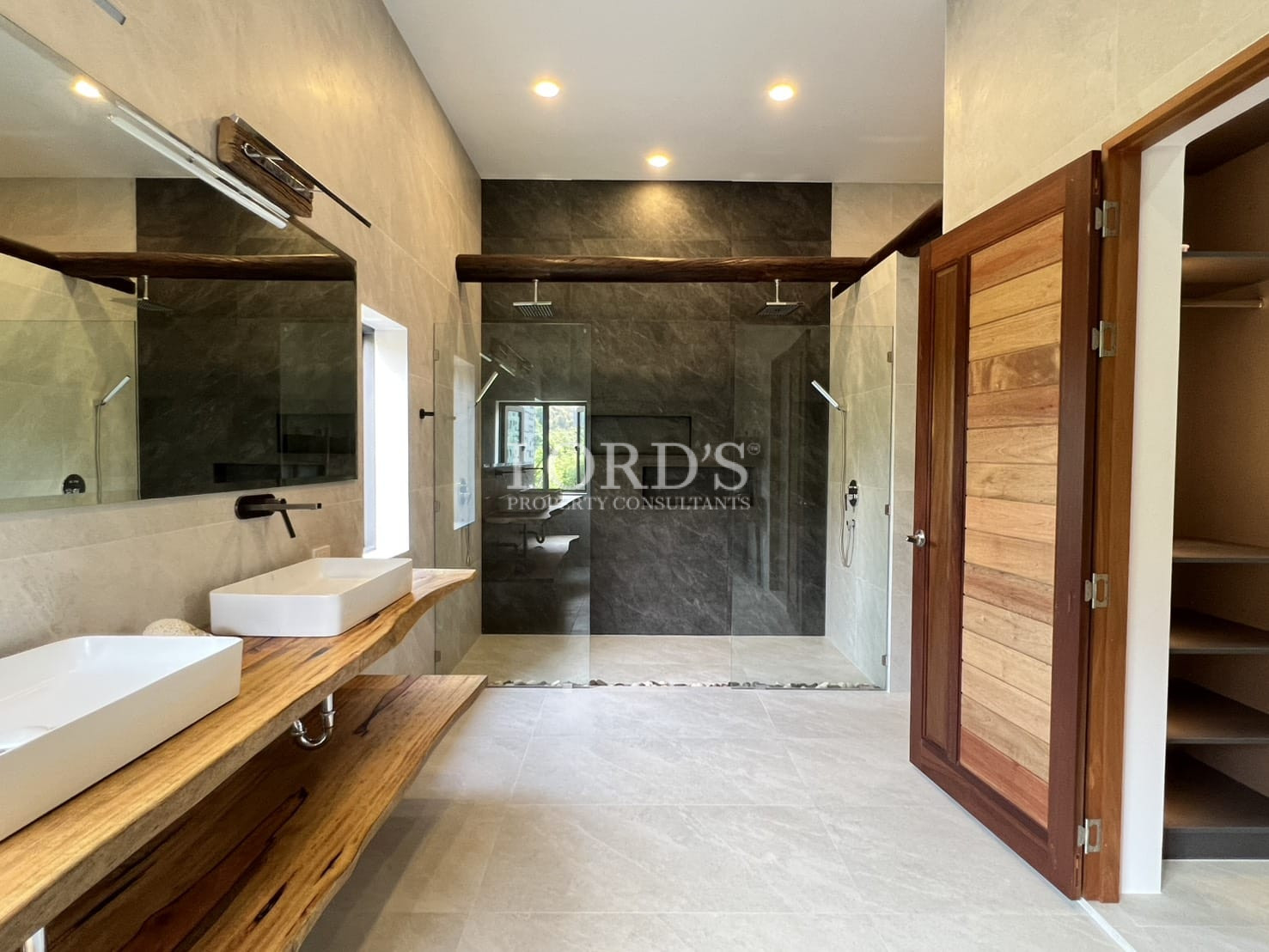 Spacious modern bathroom with double vanity, wooden countertop, and glass walk-in shower.