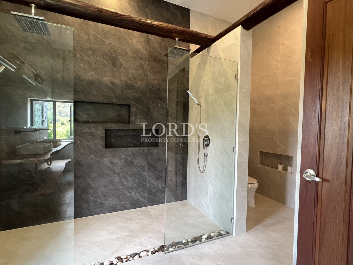 Modern bathroom with glass-enclosed walk-in shower, stone tile walls, and rainfall showerhead.