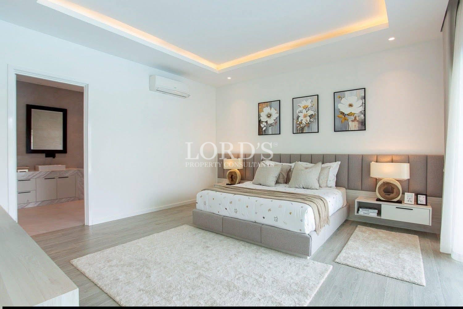 Modern bedroom with upholstered bed, floral wall art, bedside lamps, and en-suite bathroom access.