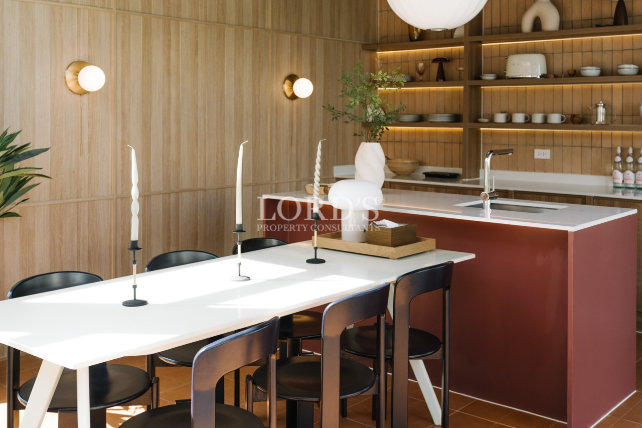 Modern kitchen and dining area with white table, black chairs, and red kitchen island.