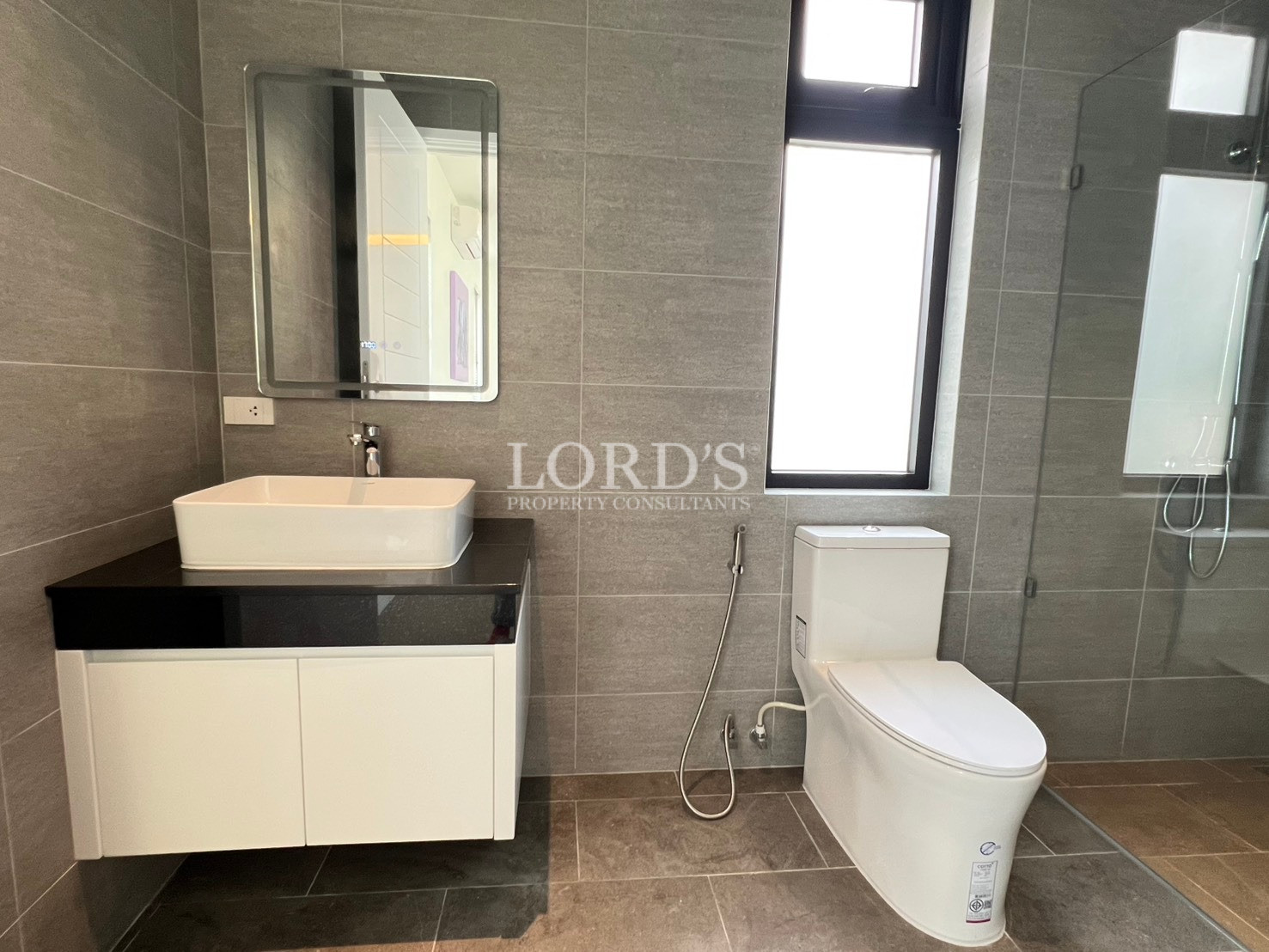 Modern bathroom with wall-mounted vanity, rectangular sink, toilet, and glass shower enclosure.