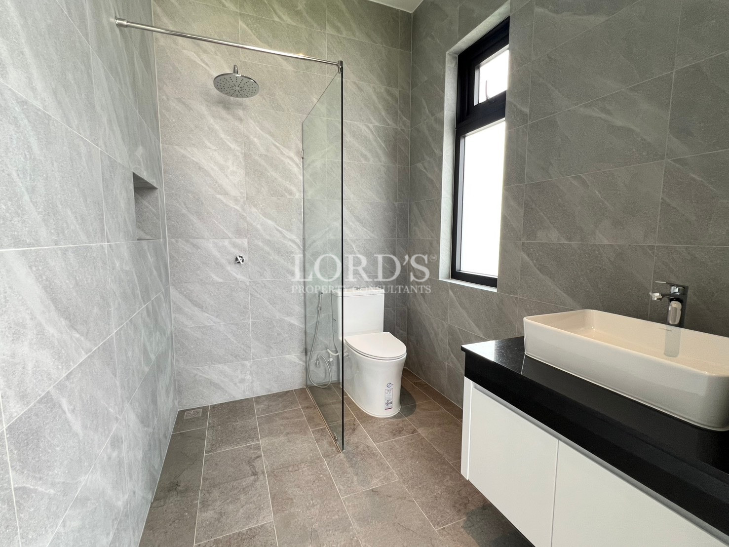 Modern bathroom with walk-in shower, glass partition, wall-mounted sink, and grey marble tiles.