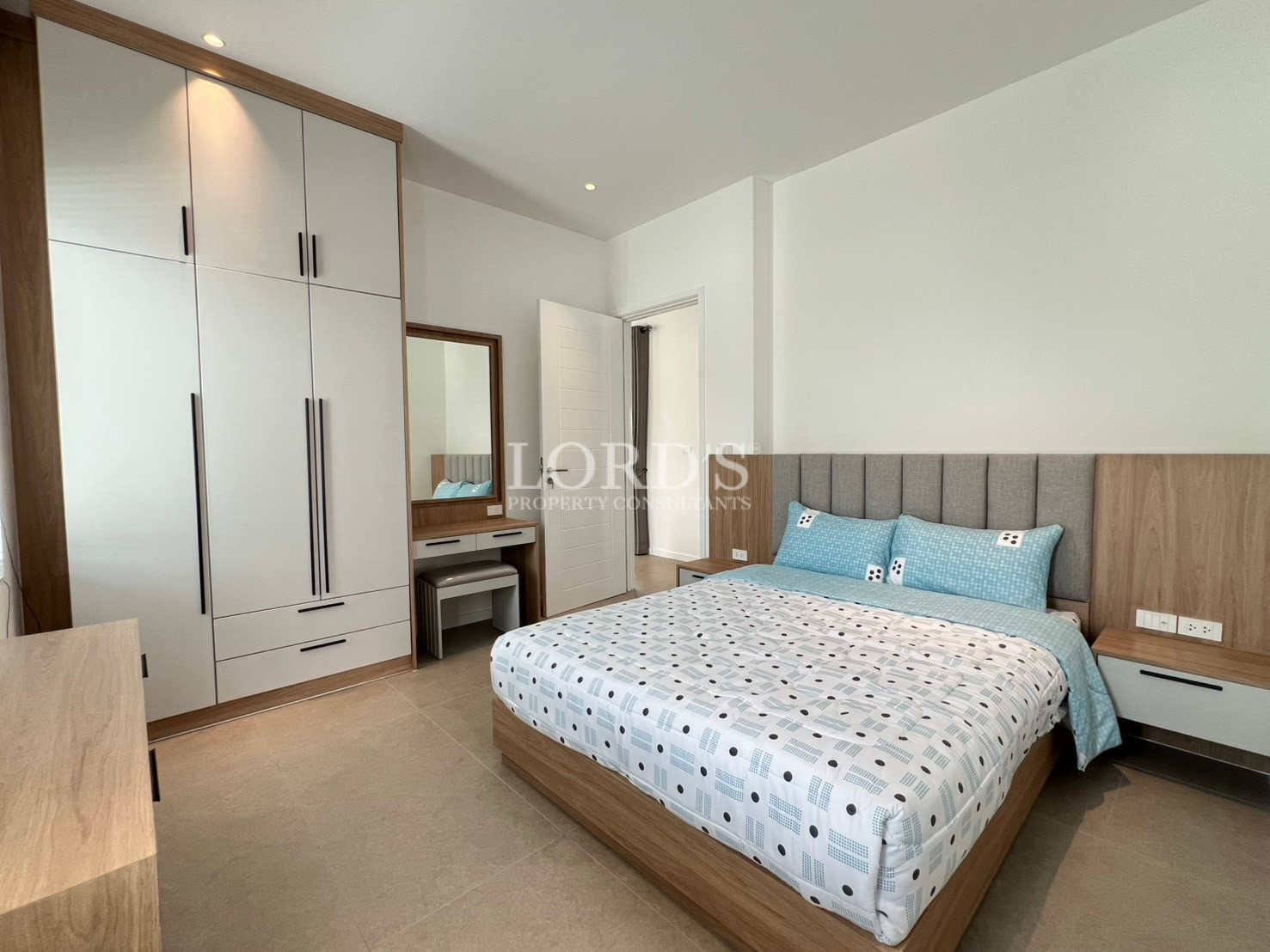 Modern bedroom with built-in wardrobe, wooden bed frame, and vanity desk.