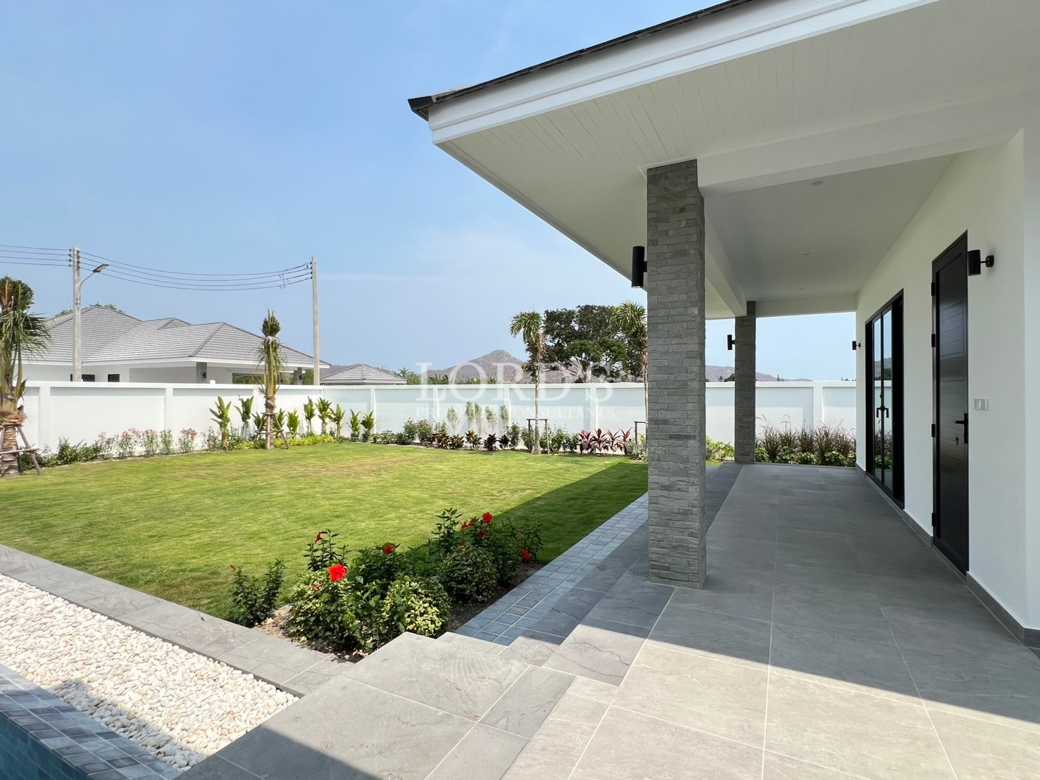 Modern villa covered terrace with garden view and landscaped lawn