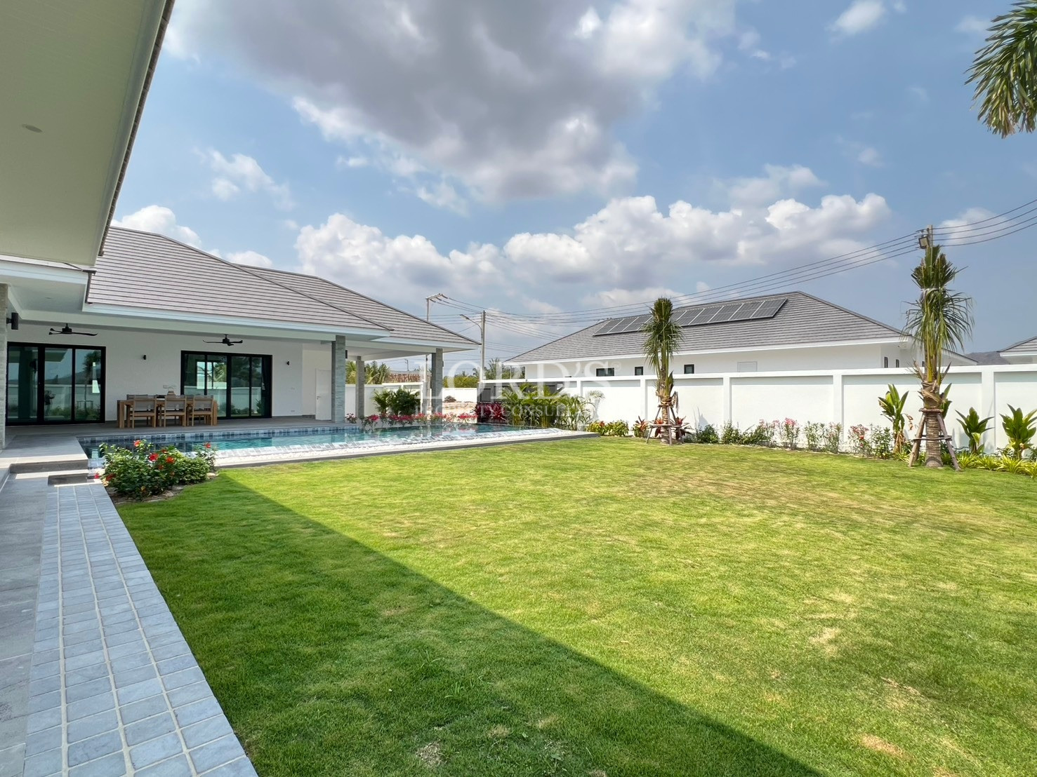 Modern villa backyard with private swimming pool and large green lawn