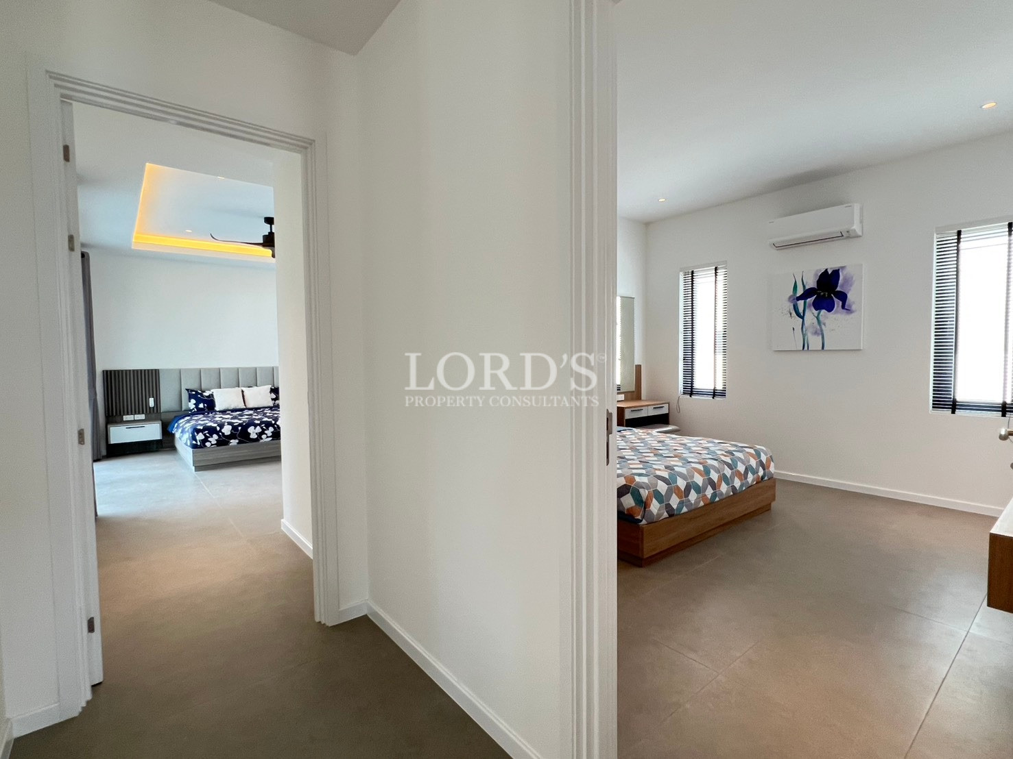 Hallway view showing two modern bedrooms with tiled flooring and bright interiors.