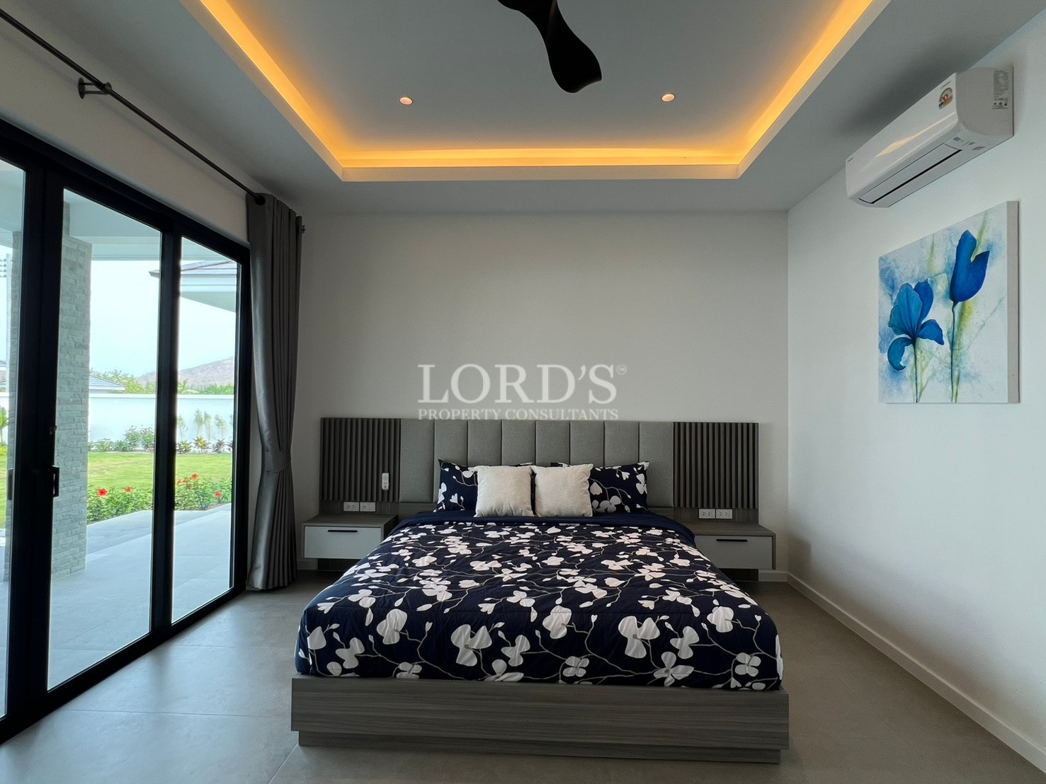 Modern bedroom with king-size bed, LED ceiling lighting, sliding glass doors, and wall-mounted air conditioner.