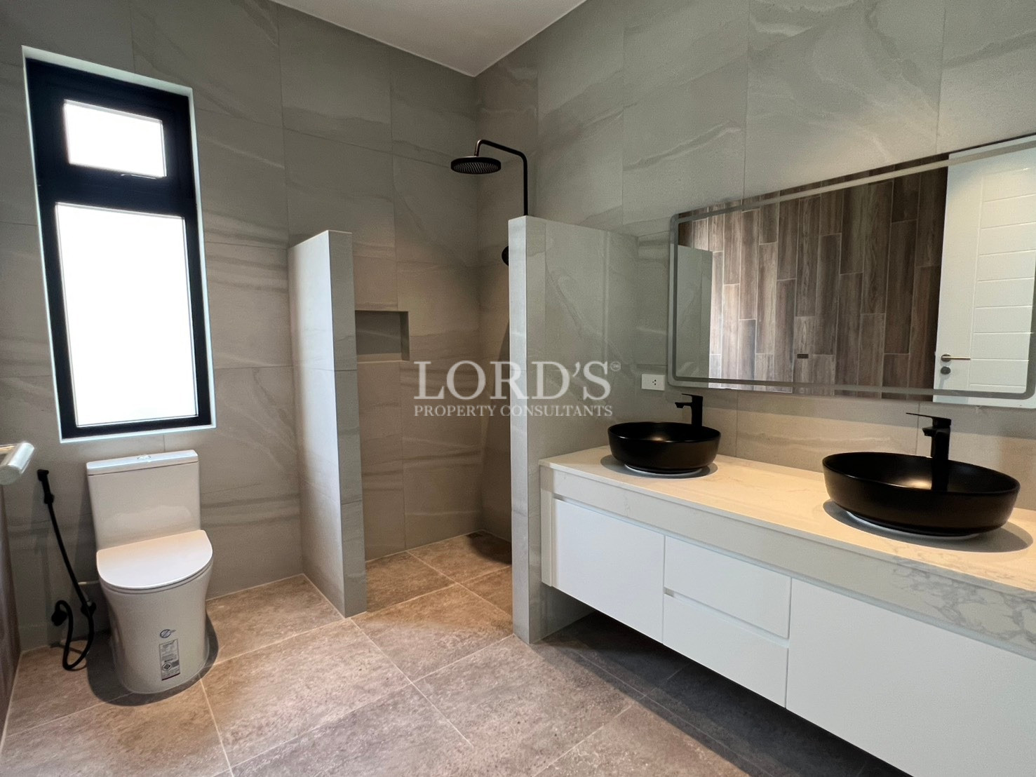 Modern bathroom with double black vessel sinks, walk-in shower, and toilet.