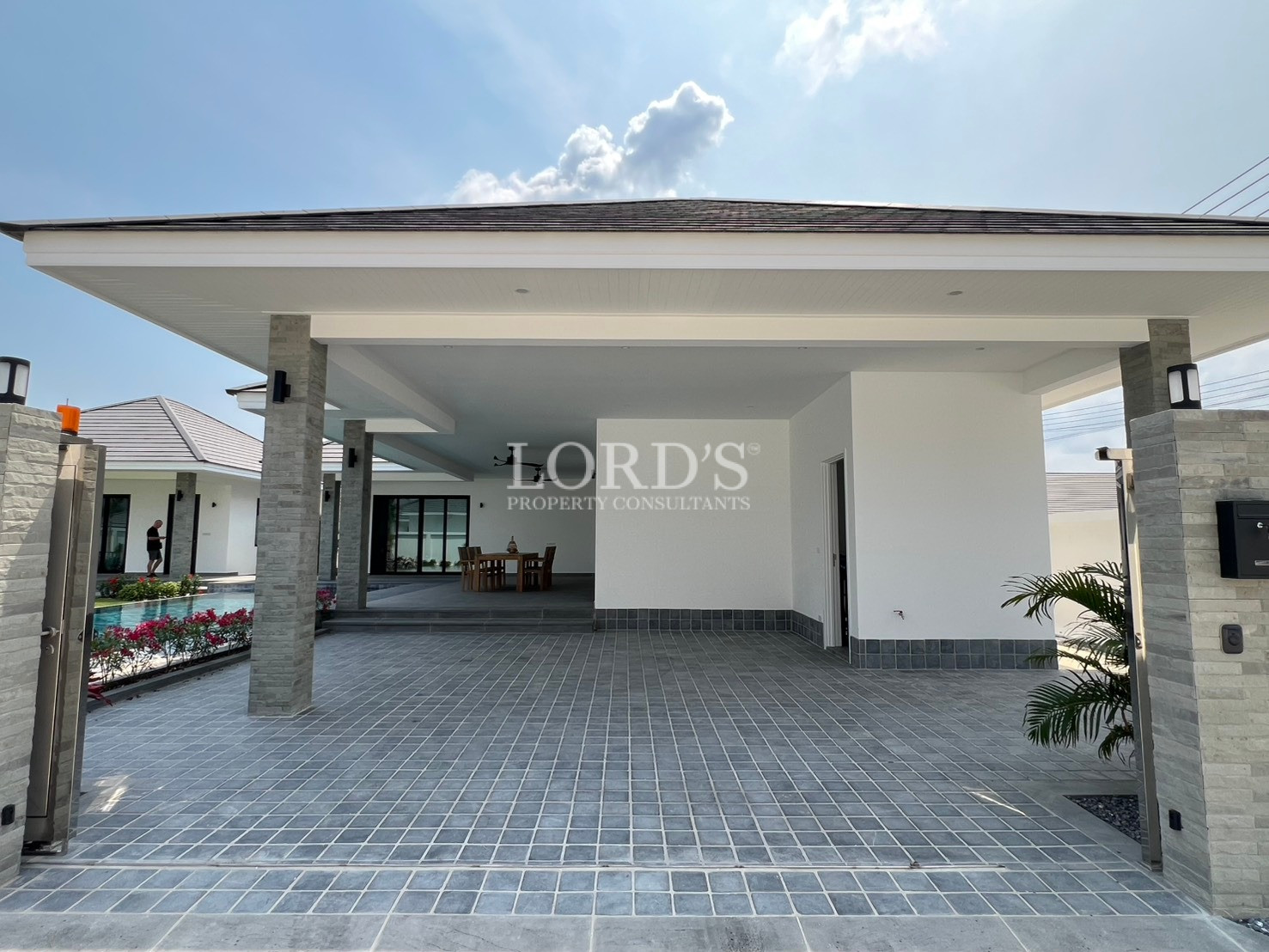 Modern villa carport and covered entrance with tiled flooring and stone pillars.