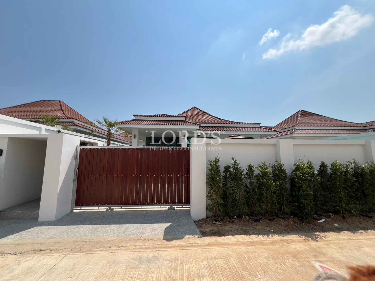 Modern single-storey villa exterior with white walls and wooden sliding entrance gate.