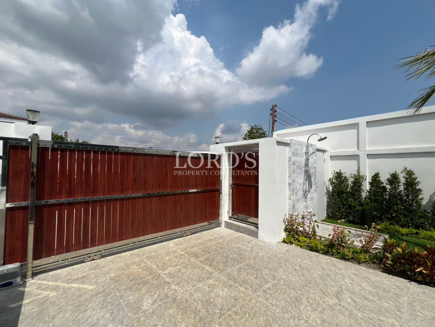 Private villa entrance with wooden sliding gate and outdoor shower area.