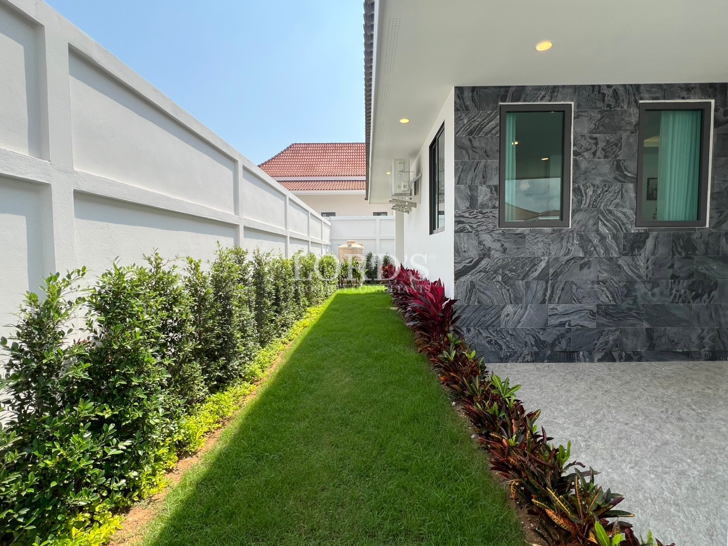 Side garden with landscaped lawn and pathway beside modern house exterior.
