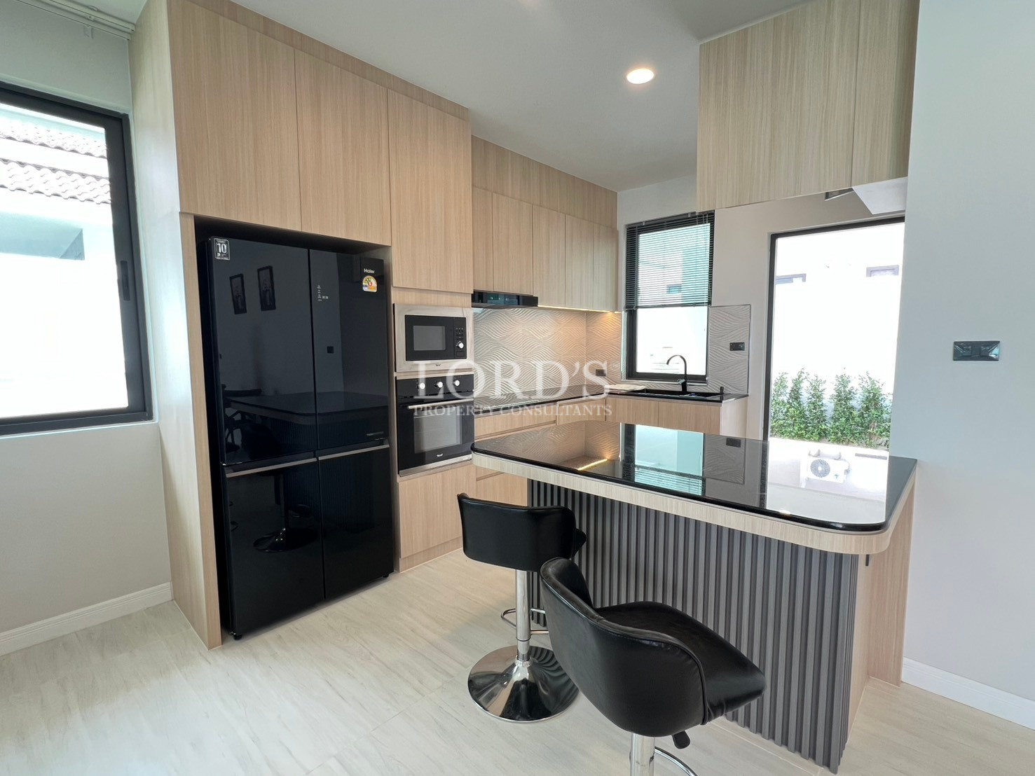 Modern kitchen with breakfast bar seating, built-in appliances, and large windows.