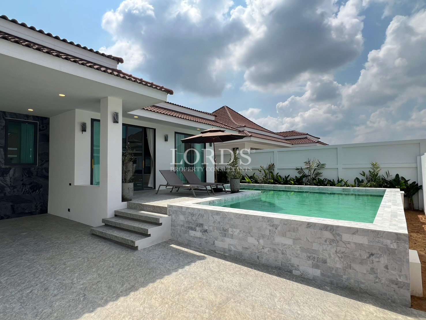 Modern villa exterior with raised private swimming pool and outdoor terrace.