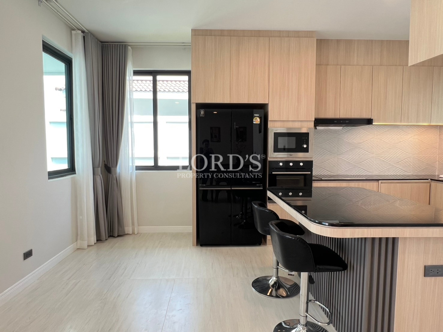 Modern kitchen with breakfast bar seating, built-in appliances, and large windows.