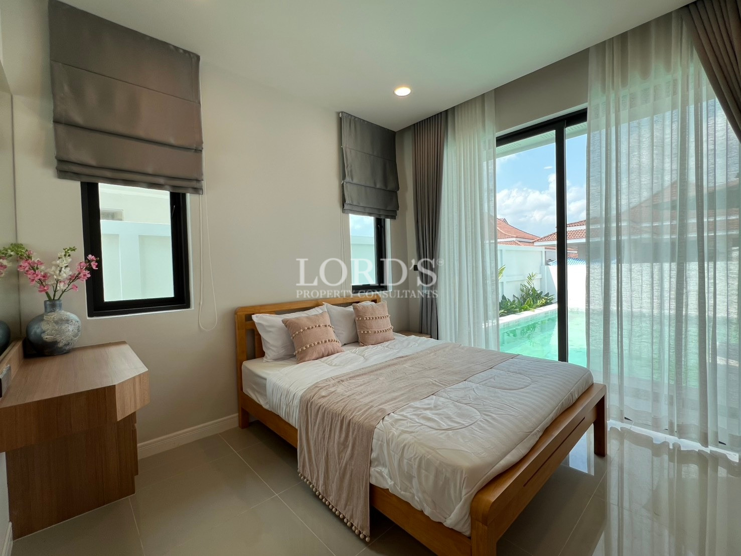 Modern bedroom with pool view, wooden bed, and sliding glass doors.