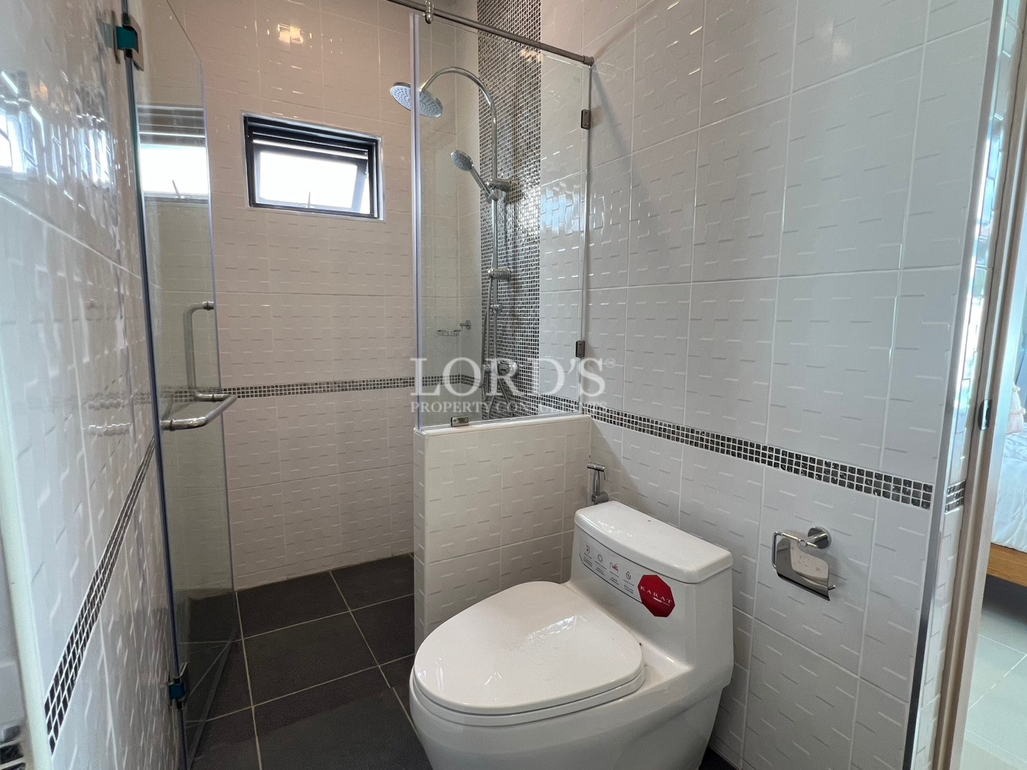 Modern bathroom with glass walk-in shower, toilet, and tiled walls.