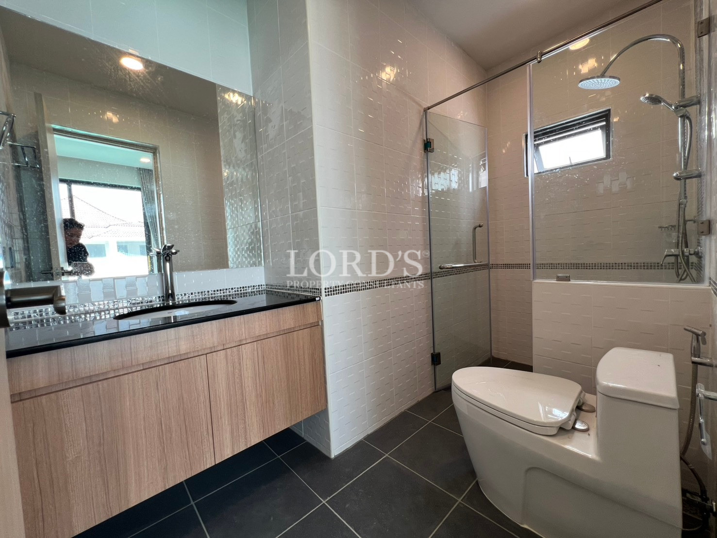 Modern bathroom with glass shower enclosure, vanity cabinet, and toilet.