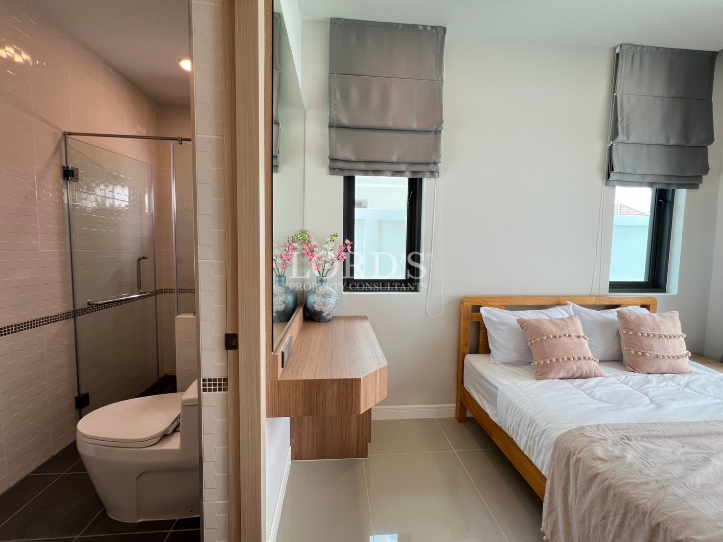 Modern bedroom with ensuite bathroom, wooden bed, and vanity desk.