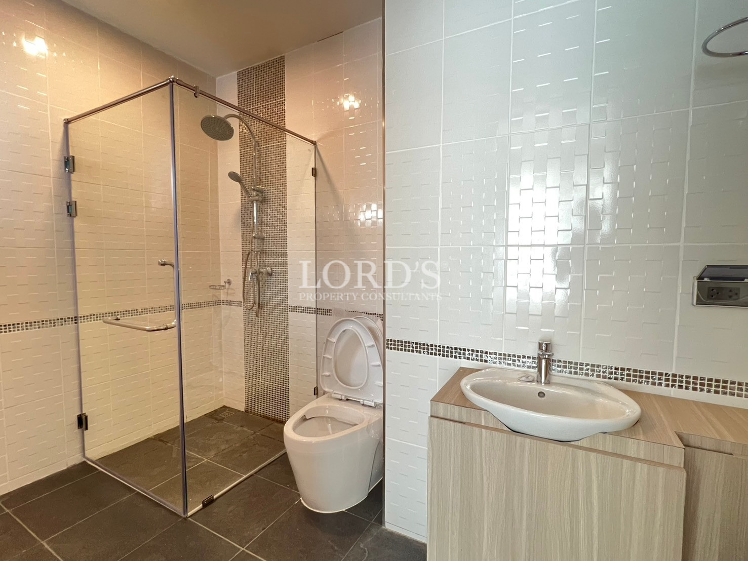 Modern bathroom with glass-enclosed shower, toilet, and vanity sink.