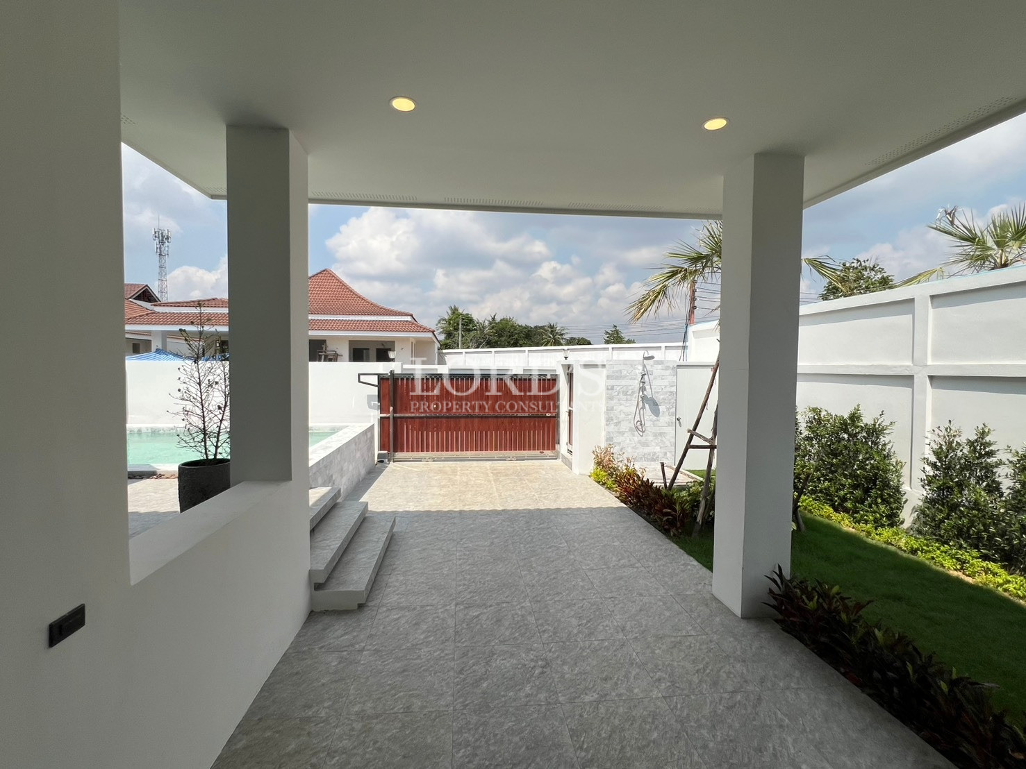 Covered outdoor terrace overlooking private pool, garden, and gated courtyard.