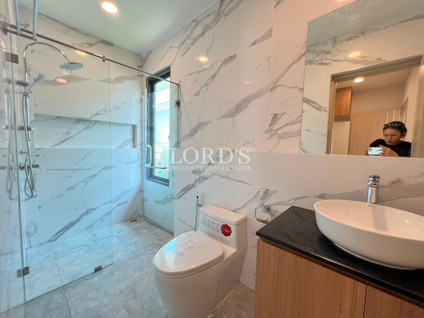 Modern bathroom with marble-look tiles, glass shower enclosure, and vanity sink.