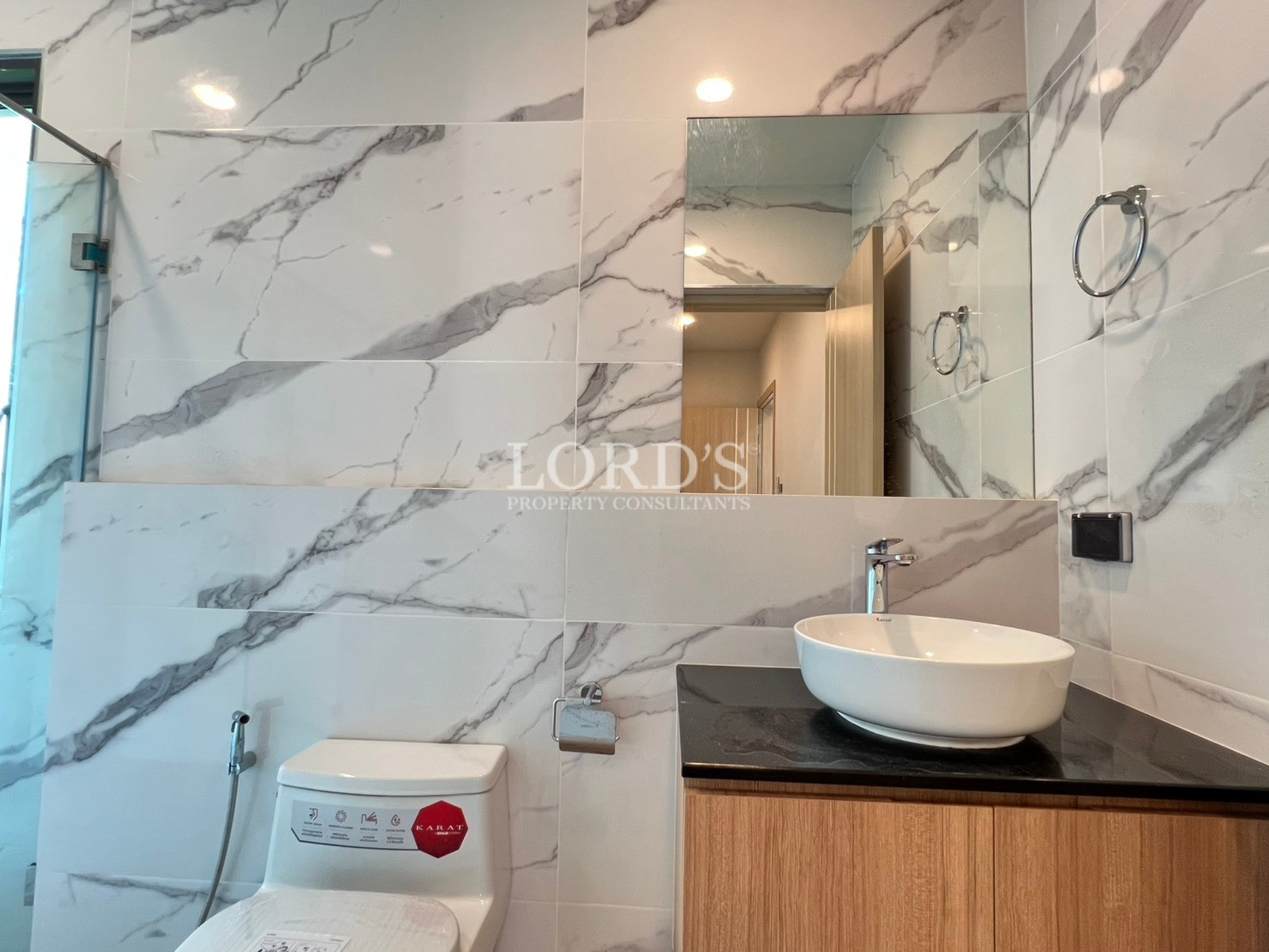 Modern bathroom with marble-look wall tiles, vanity sink, and glass shower enclosure.