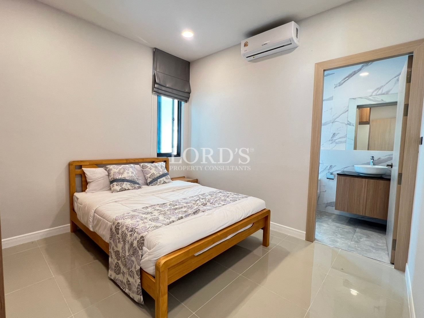 Modern bedroom with wooden bed, air conditioning, and ensuite bathroom.