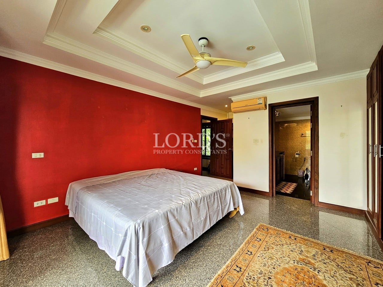 Master bedroom with red accent wall and large bed