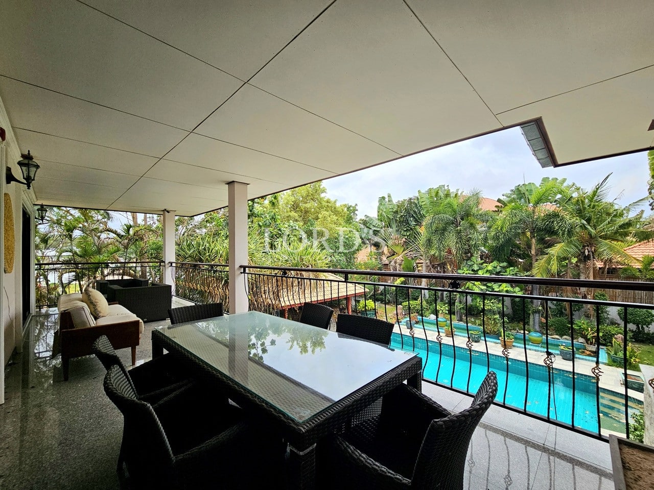 Covered terrace balcony with outdoor dining overlooking swimming pool