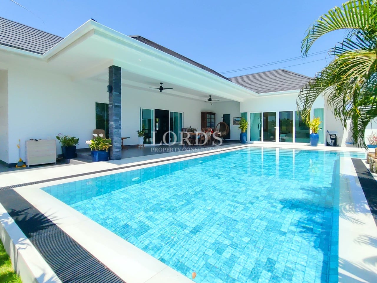 Modern swimming pool with villa backdrop