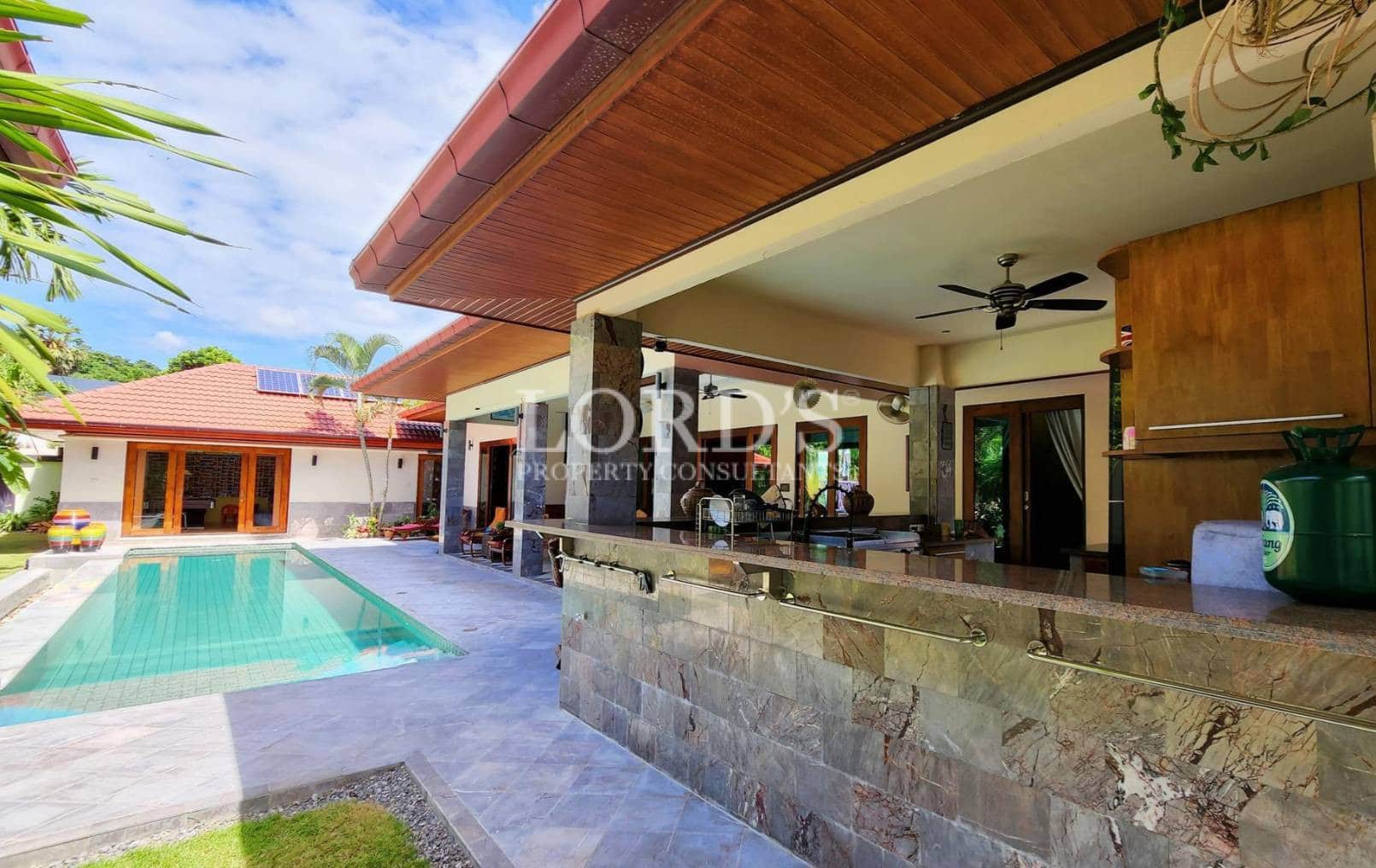 Outdoor kitchen and bar area beside pool