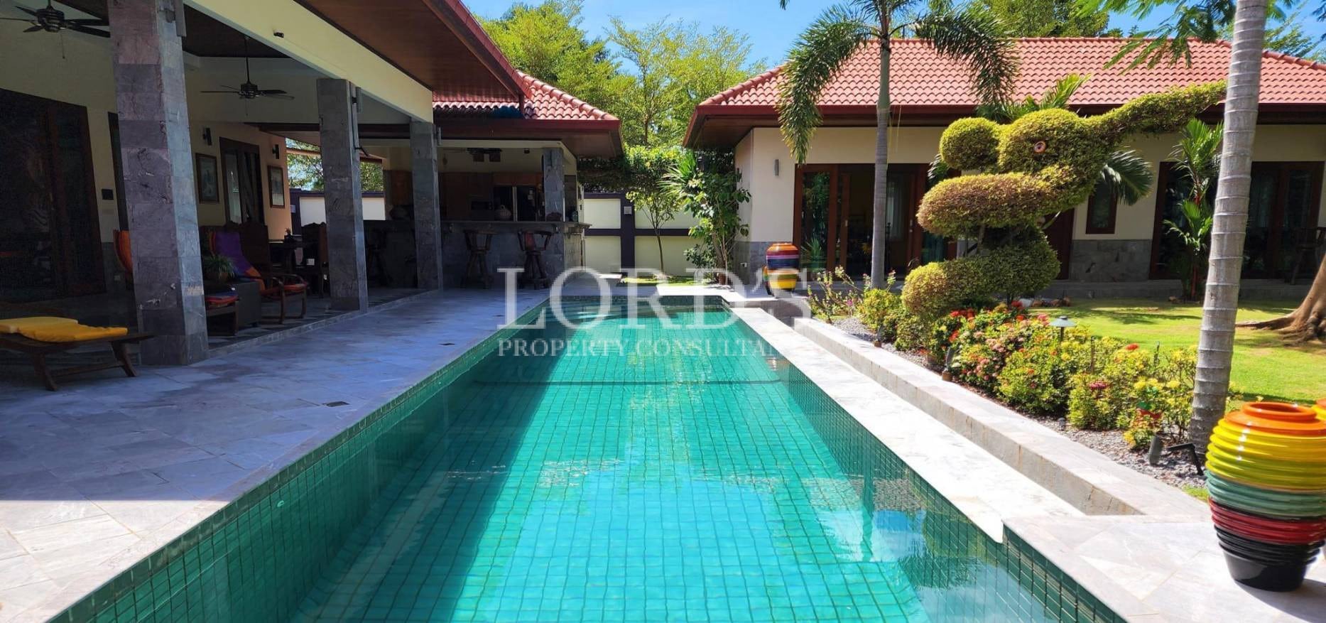 Long swimming pool with villa and garden