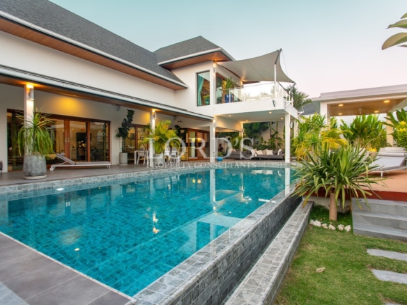 Pool with villa and tropical landscaping