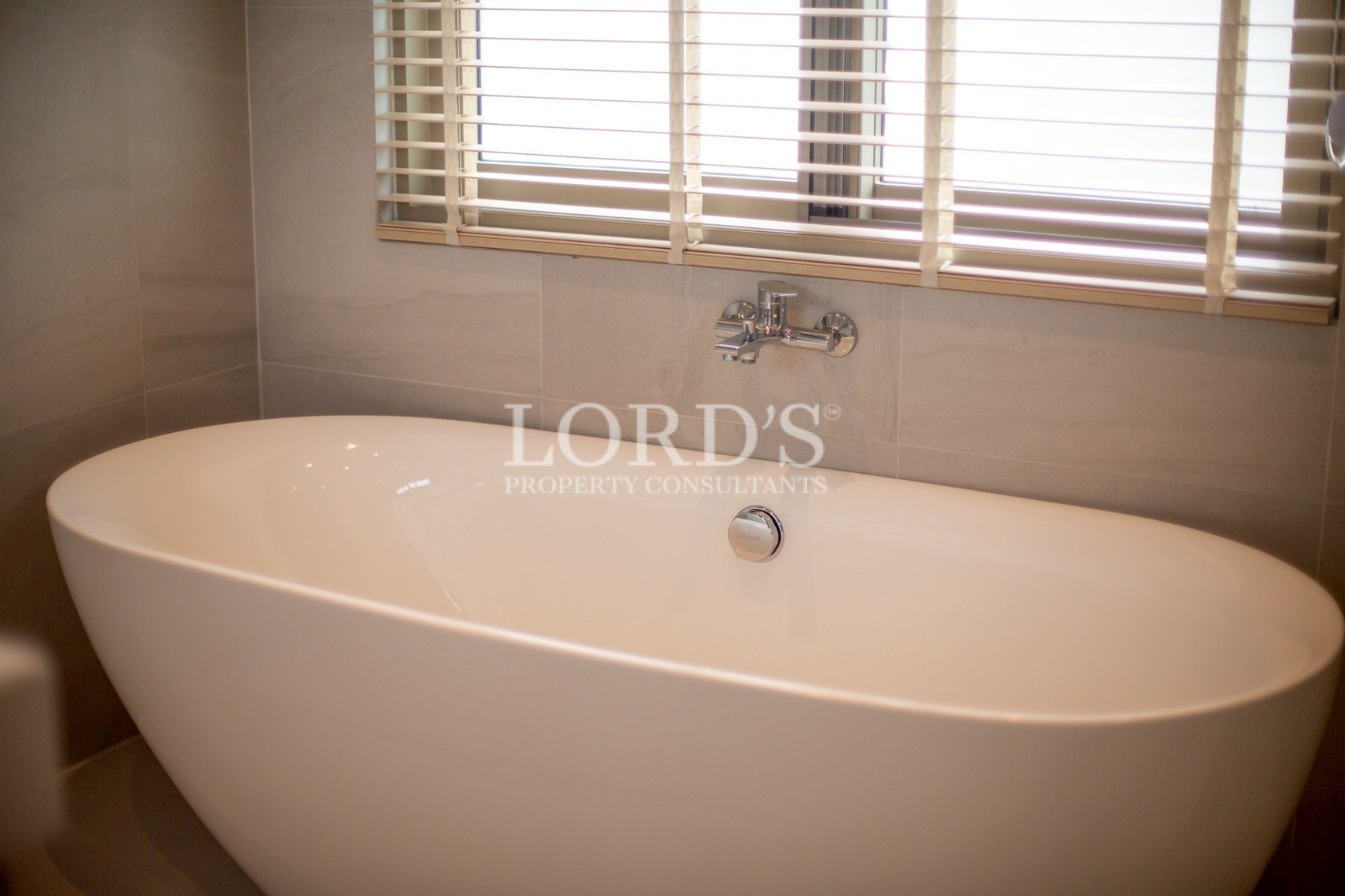 Freestanding bathtub near window blinds