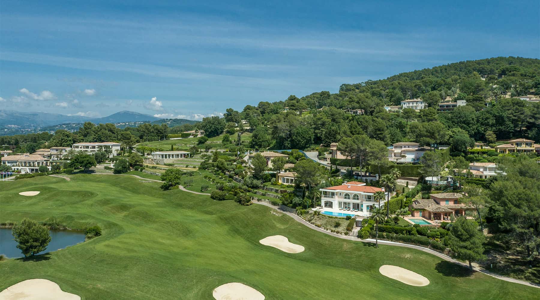 Luxury villas overlooking golf course with scenic hills and greenery