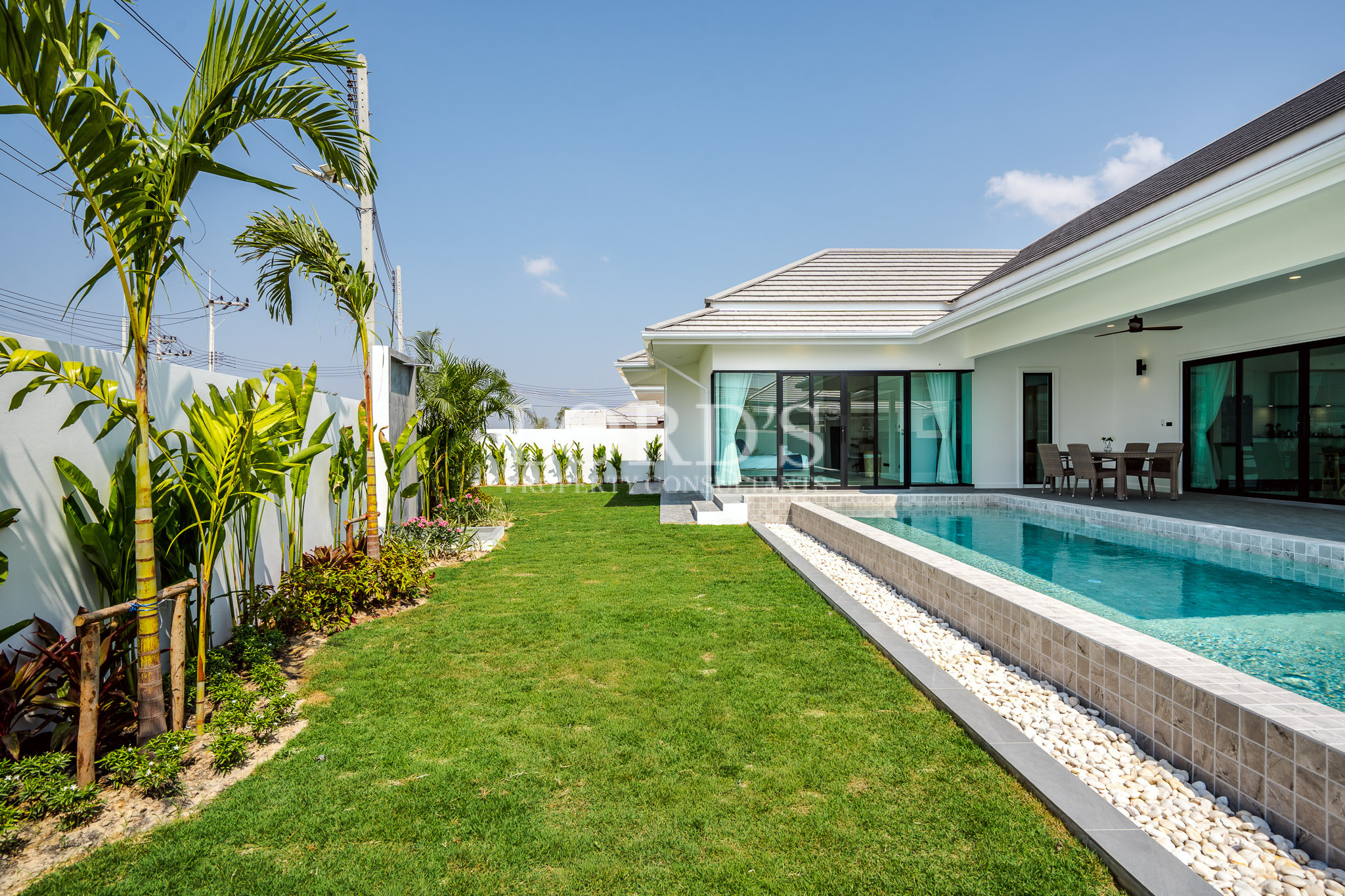 Modern villa exterior with pool and landscaped lawn
