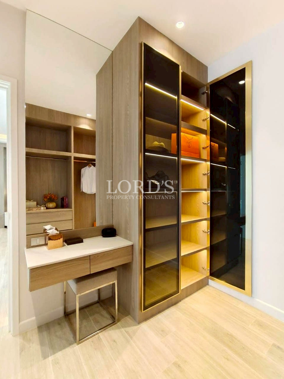 Walk-in closet with illuminated shelving and vanity