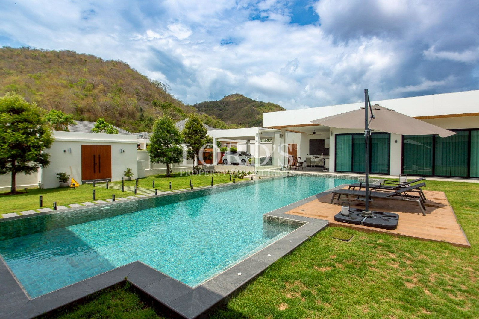 Swimming pool beside modern villa and mountains