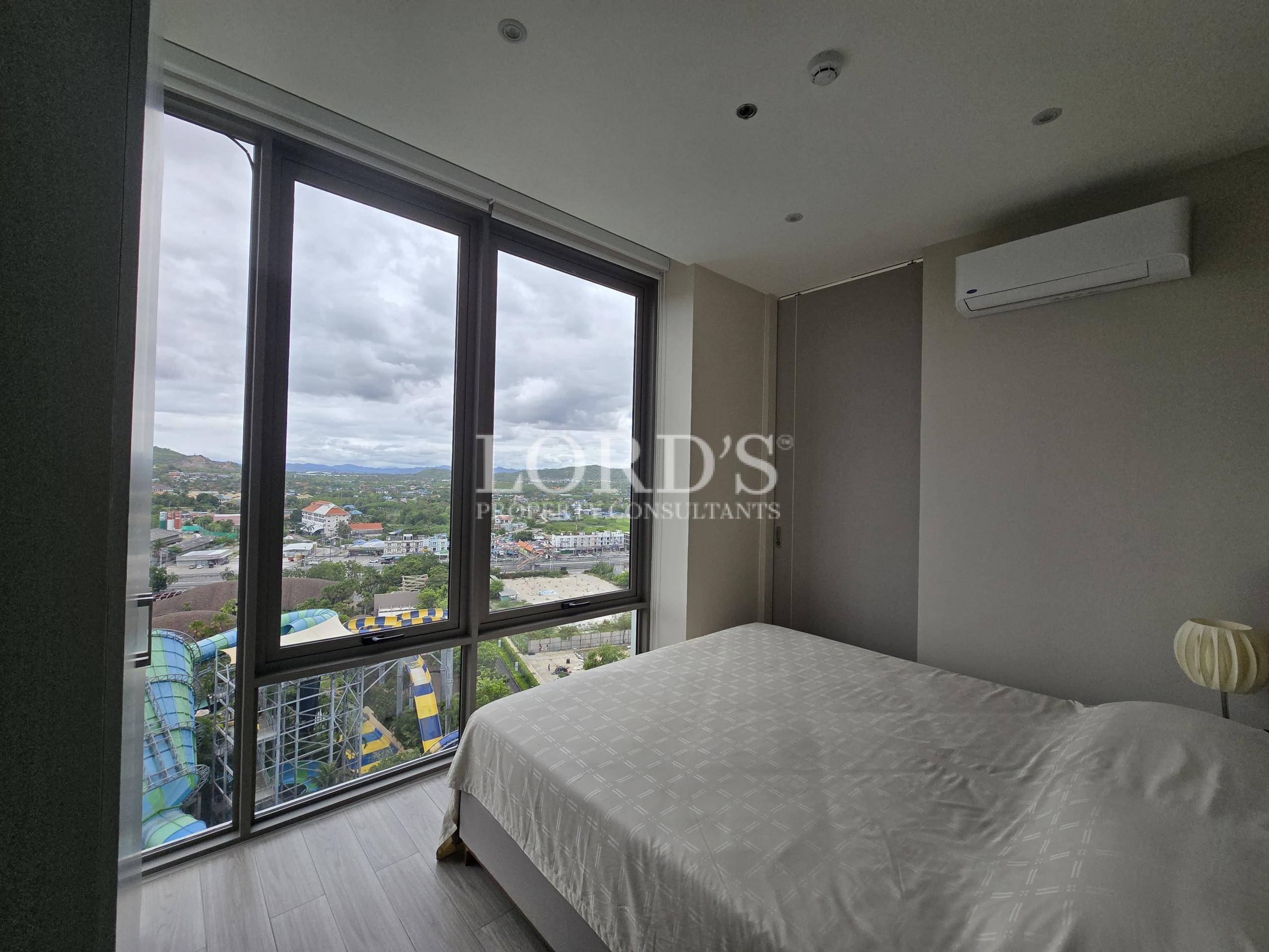Bedroom with large windows and city skyline