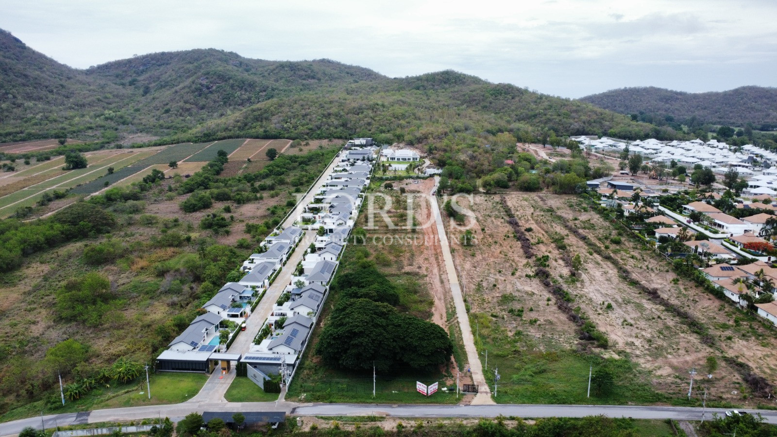 Long aerial view of villas and green hills